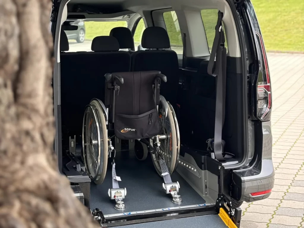 Behindertengerechtes Auto beim Spezialisten testen: Rollstuhl mit Rückhaltesystem im Heck eines umgebauten VW Caddy Maxi